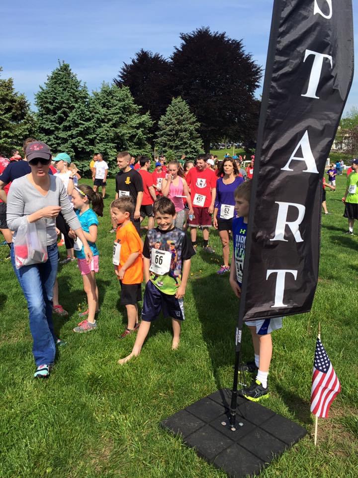 Young runners lined up beside a START banner at a community race